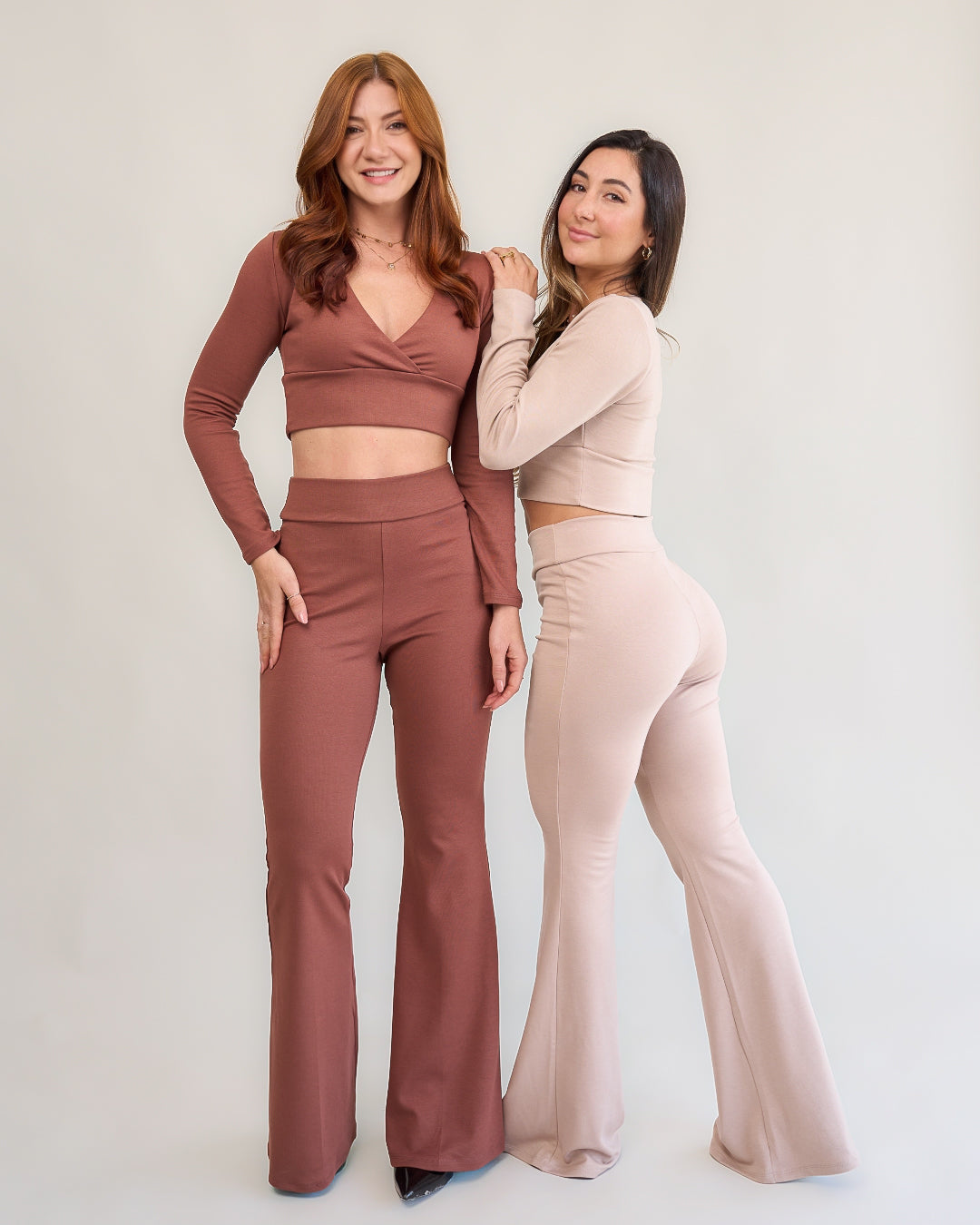 Duas modelos usando conjuntos flare marrom e nude look completo