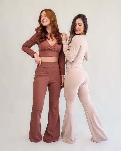 Duas modelos com conjuntos flare marrom e nude posando juntas