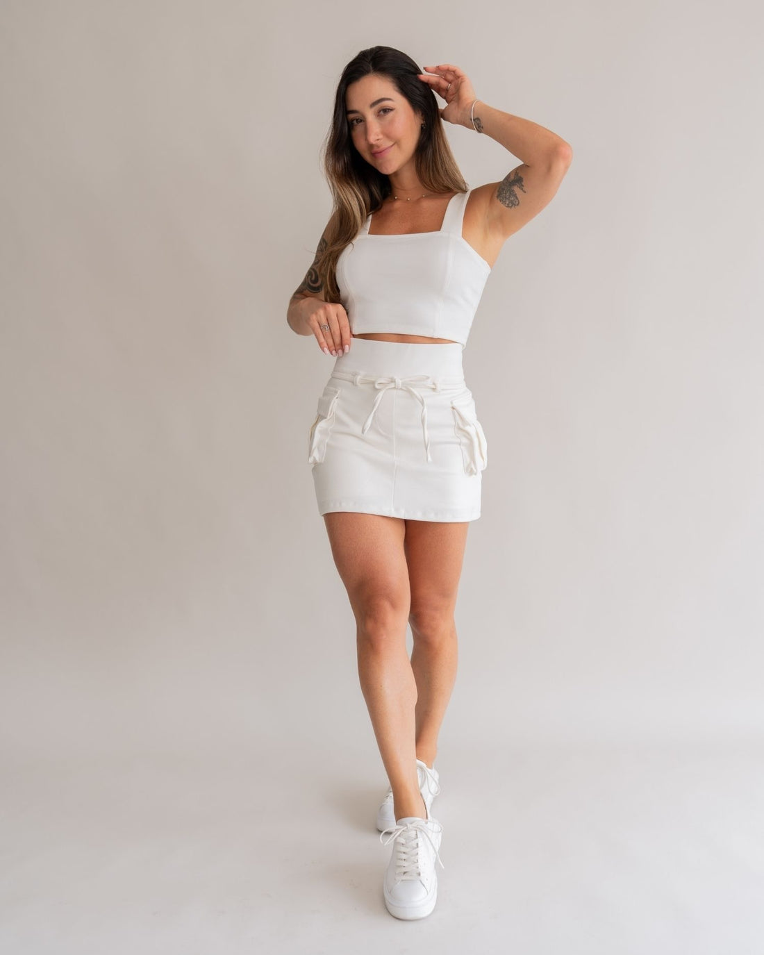 Short saia cargo off white branco feminino look frontal sorrindo conjunto top cargo tênis