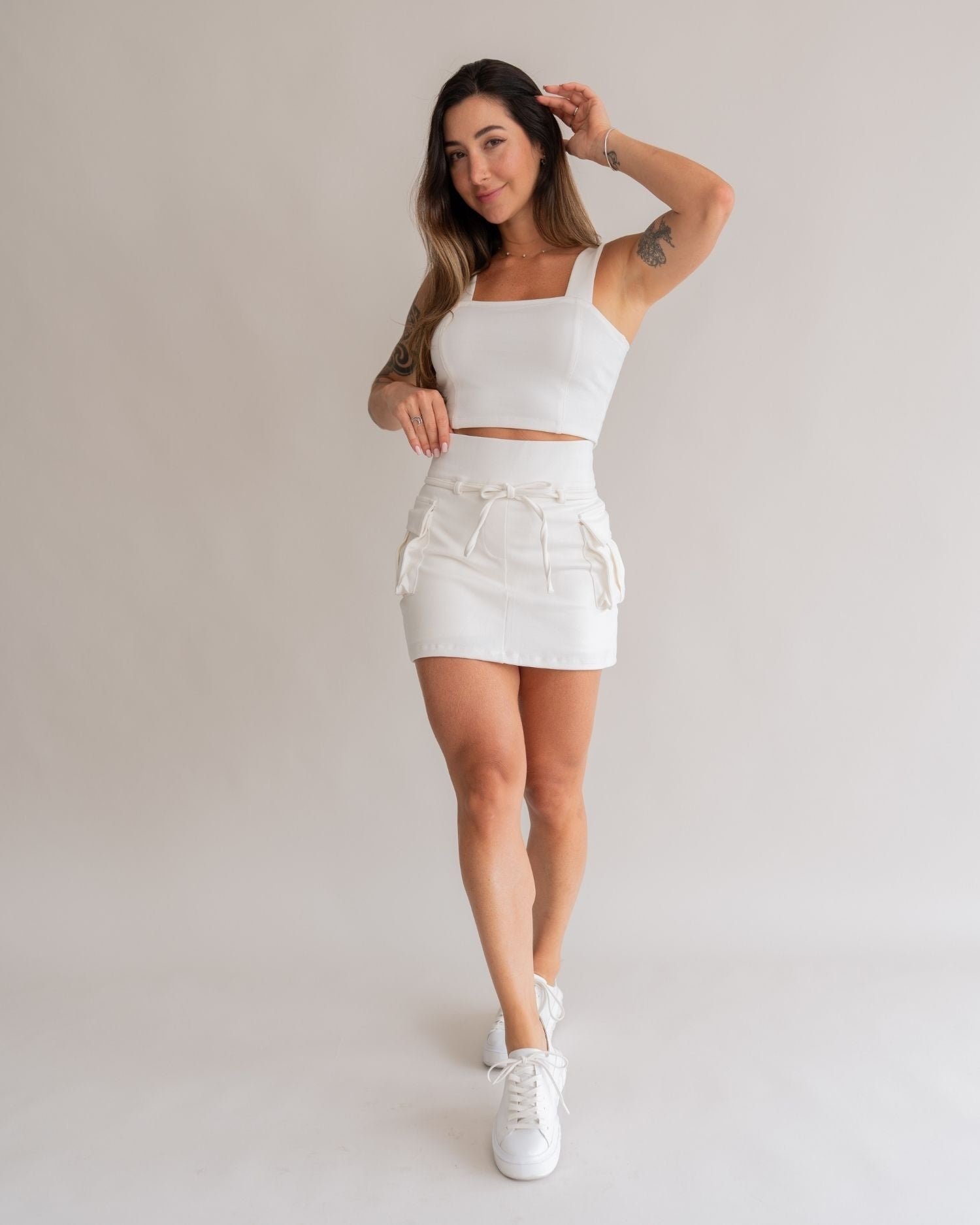 Short saia cargo off white branco feminino look frontal sorrindo conjunto top cargo tênis