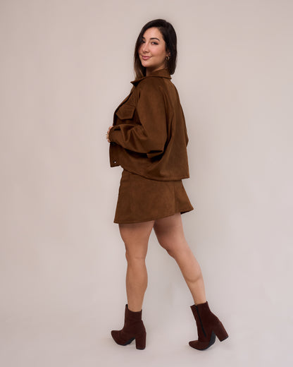 Saia curta suede caramelo feminino look lateral com jaqueta over caramelo e bota marrom salto